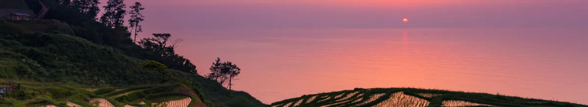 Ein idyllischer Sonnenuntergang über dem Meer bei Wajima, der den Himmel in lila Farben tränkt.