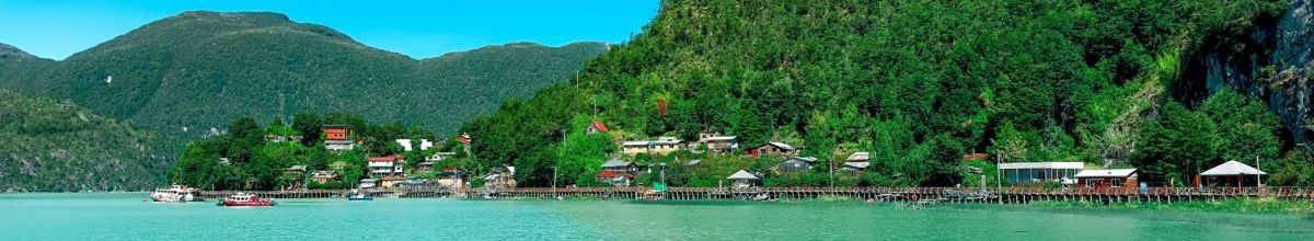 Grüne Küste von Caleta Tortel mit kleinen Häusern und Holzstegen.