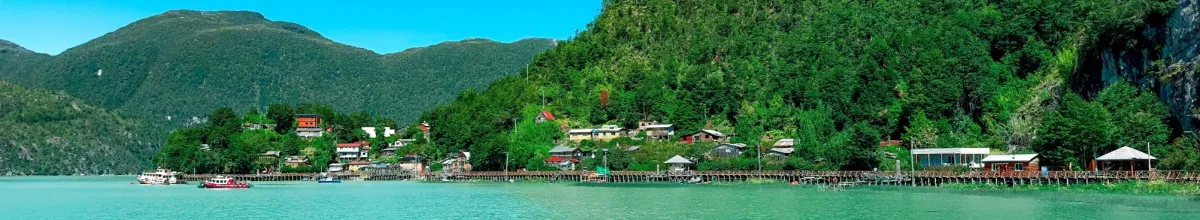 Grüne Küste von Caleta Tortel mit kleinen Häusern und Holzstegen.