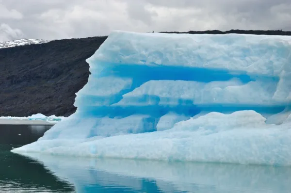 Seitenansicht eines weiß-blauen Eisbergs nahe des Jorge-Montt-Gletschers, der über das Meer treibt.
