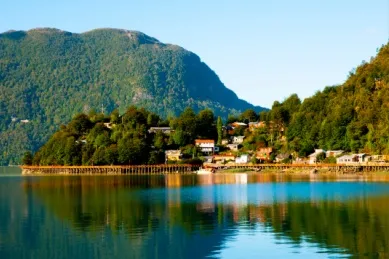 Grüne, hügelige Küste mit Blick auf das Fischerdorf Caleta Tortel in Chile.