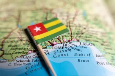Flagge von Togo liegt auf der Landkarte, auf der die Stadt Lomé abgebildet ist.