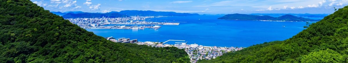 Panoramablick über grüne Hügel auf die Stadt und die Bucht von Takamatsu.
