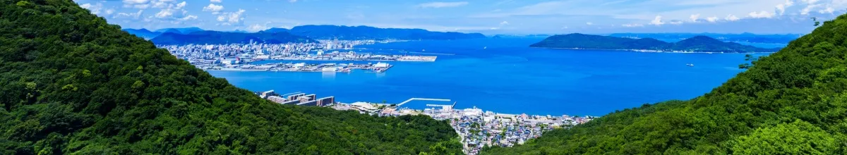Panoramablick über grüne Hügel auf die Stadt und die Bucht von Takamatsu.