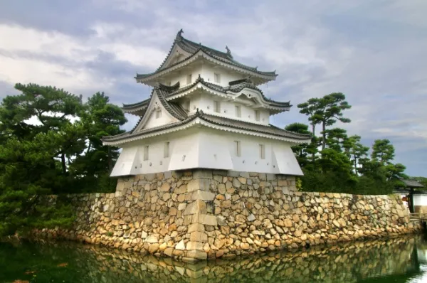 Ruine der Wasserburg von Takamatsu, die nur von einer alten Burgmauer vom Wasser getrennt wird.