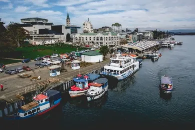 Boote am Ufer von Valdivia, im Hintergrund sieht man Gebäude und eine Kirche.