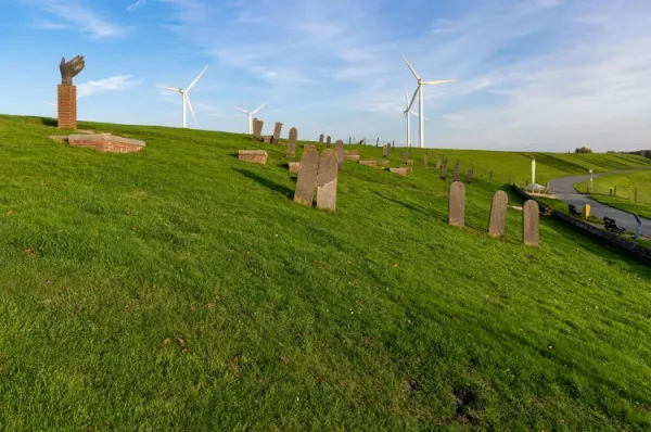 Monumente Delfzijl Monumente in den grünen Hügeln bei Delfzijl, im Hintergrund Windräder.