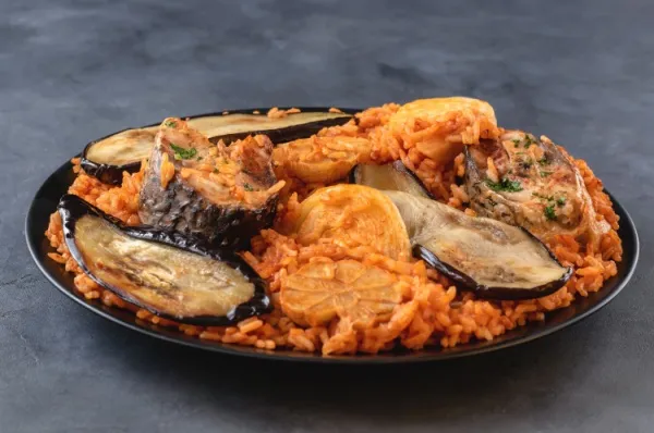 Traditionelles Gericht aus Westafrika mit Fisch, Reis und Tomatensauce zubereitet, in einem Topf gekocht.