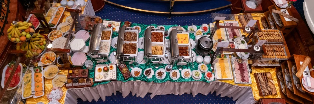 Buntes Frühstücksbuffet aus der Vogelperspektive. Unter anderem mit verschiedenen Obstsorten, Brot & Gebäck, verschiedenen Wurst- & Fleischarten, Käse, Joghurt und Marmeladen