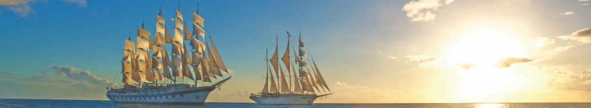 Seitenansicht der beiden Großsegler Royal Clipper und Star Clipper auf dem Meer. Rechts die untergehende Sonne.