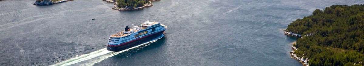 Die MS Midnatsol fährt an der Küste Norwegens entlang und hinterlässt Wellen im Meer.