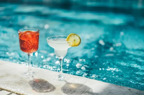 Zwei Cocktails stehen am Rand eines Pools auf dem Deck eines AIDA Schiffs. Die Getränkepakete sind im AIDA COMFORT ALL IN Tarif bereits inklusive.