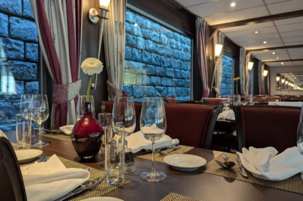 Blick aus dem eleganten Bordrestaurant der MS VistaNova auf die beleuchtete Steinmauer einer Schleusenkammer während der Durchfahrt.