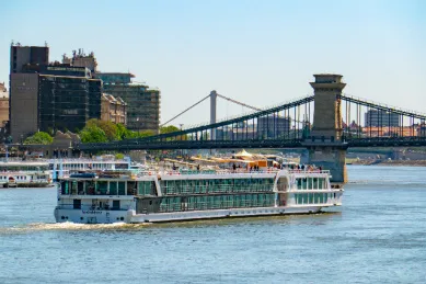 Das Flusskreuzfahrtschiff MS VistaNova von 1AVista Reisen fährt auf der Donau vor der Skyline von Budapest mit der berühmten Kettenbrücke im Hintergrund.