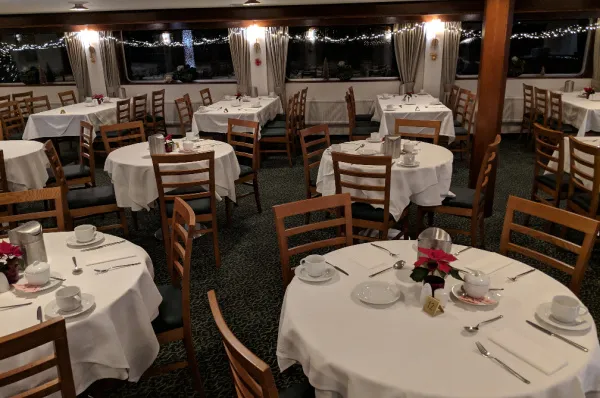 Festliches Restaurant der MS VistaClassica Das Bordrestaurant der MS VistaClassica mit festlich gedeckten, runden Tischen, weißen Tischdecken und kleinen Weihnachtsgestecken, bereit für die Gäste am Abend.