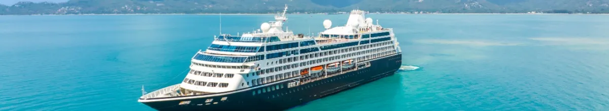 Das Kreuzfahrtschiff fährt ins türkisblaue Wasser.