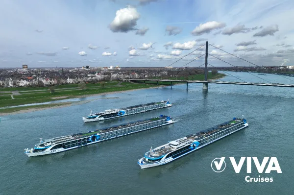 Elegante Flussschiffe der Lifestyle-Reederei VIVA Cruises im direkten Vergleich Drei moderne VIVA Cruises Flusskreuzfahrtschiffe fahren nebeneinander auf dem Rhein vor einer Brücken-Kulisse im Flusskreuzfahrt-Anbieter-Vergleich.