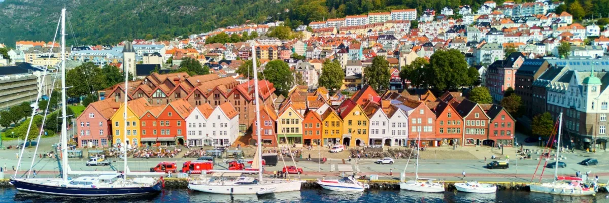 WM Kreuzfahrten nach Nordeuropa: Urlaubsweltmeister in Norwegen & Co. 3 Segelboote und 3 Motorboote vor der Waterfront von Bergen mit den bunten Holzhäusern des Stadtteils Bryggen.