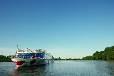 A-ROSA Schiff auf dem Rhein mit dicht bewaldeten Ufern links und rechts