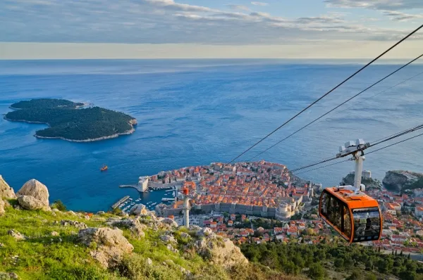 Die Altstadt von Dubrovnik am Meer mit roter Seilbahn, die vom Berg hinunterfährt.