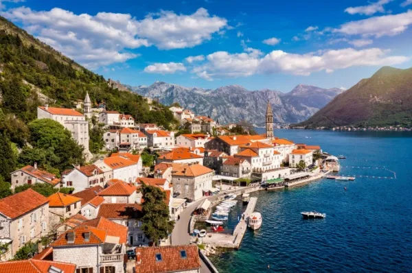 Altstadt von Kotor am blauen Wasser, im Hintergrund Berglandschaften.