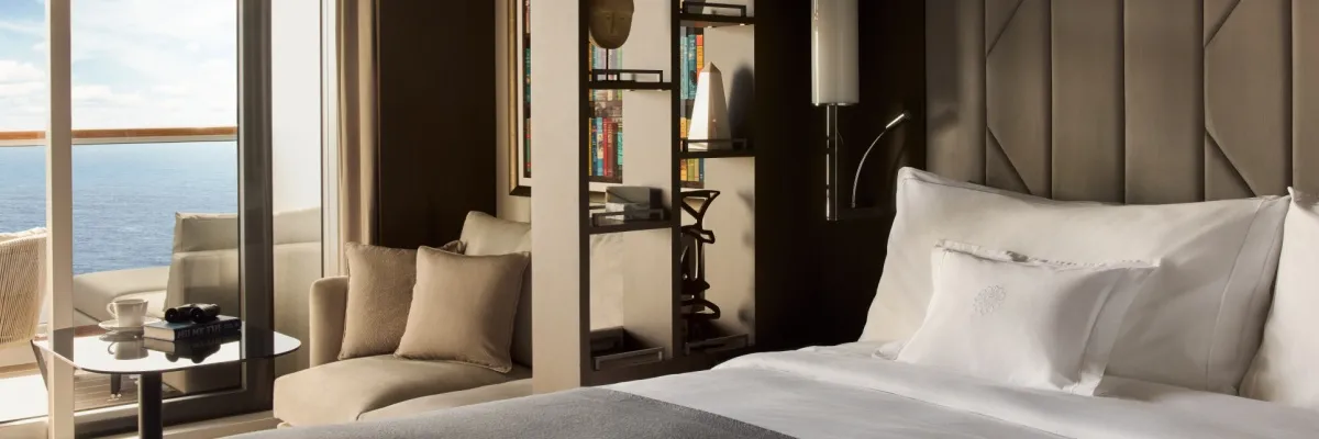 EXPLORA Ocean Terrace Suite Beispielbild einer Ocean Terrace Suite mit einem gemütlichen Doppelbett, einem Regal als Raumtrenner und einem Ausblick auf das Meer über den Balkon.