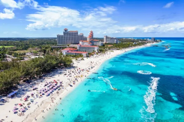 Türkisfarbenes Meer und Sandstrand, im Hintergrund hohe Gebäude.