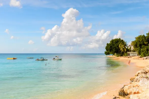 Traumhaftes klares Wasser an feinem Sandstrand, auf dem Wasser kleine Boote.