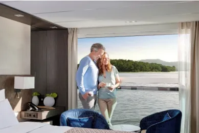 AMADEUS Flusskreuzfahrten erleben Ein paar Steht in ihrer Kabine auf einem AMADEUS Schiff und genießt die Flusskreuzfahrt.