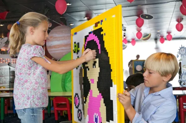 Zwei Kinder bauen ein Bild aus Legosteinen.