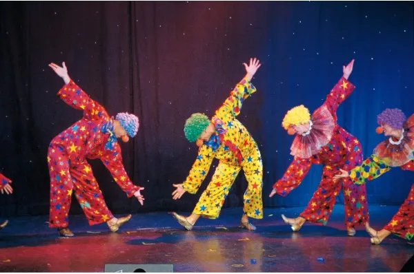 Vier Personen als Clowns verkleidet performen auf einer Bühne.