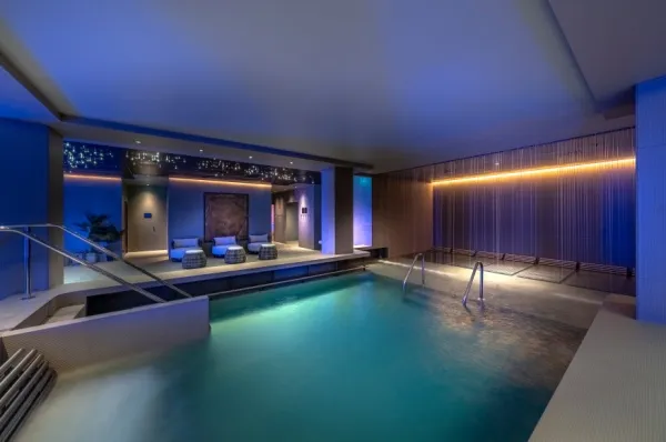 Top 5 Kreuzfahrtschiffe für Wellness und Erholung Platz 1 MSC World Europa MSC Aurea Spa mit Pool unter abgedunkeltem Licht und Liegeflächen.