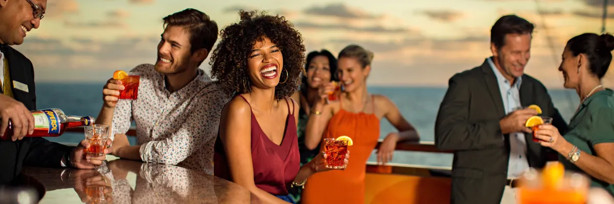Mediterrane Abende an Bord: Gesellige Stunden und Aperitivo bei Sonnenuntergang mit Costa Gäste genießen bei Sonnenuntergang einen Aperitif an der Freiluft-Bar an Bord eines Costa-Kreuzfahrtschiffs.