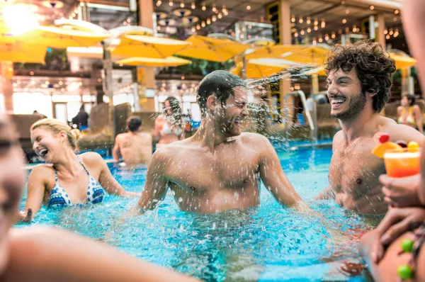 Badespaß und Entspannung: Lebhafte Urlaubsstimmung auf dem Pooldeck von Costa Kreuzfahrten Gut gelaunte Urlauber erfrischen sich im überdachten Poolbereich an Bord eines Costa-Kreuzfahrtschiffs.