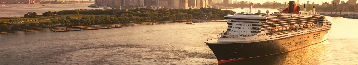 Das Cunard-Kreuzfahrtschiff Queen Mary 2 fährt bei Sonnenuntergang im Hafen von New York, im Hintergrund ist die beleuchtete Skyline von Manhattan zu sehen.