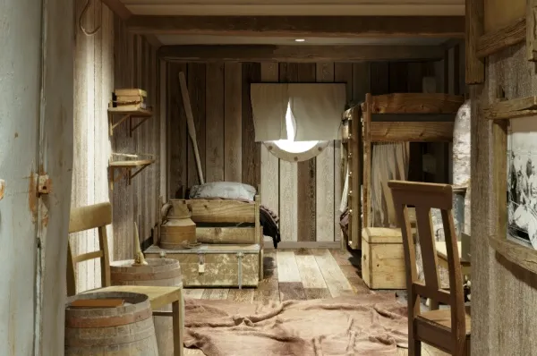 Die historische 1896 Kabine Die Ansicht aus der Tür: Ein Stockbett und ein Einzelbett mit originaler Dekoration und einem kleinen Bullauge.