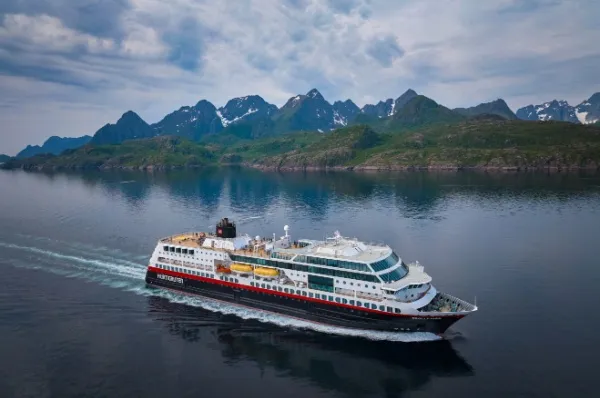 Die MS Trollfjord schippert über das Wasser, im Hintergrund sieht man Berglandschaften.