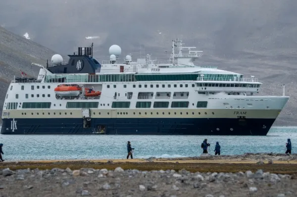 Die MS Fram vor Gletschern, im Vordergrund sieht man einige Personen an der Küste.