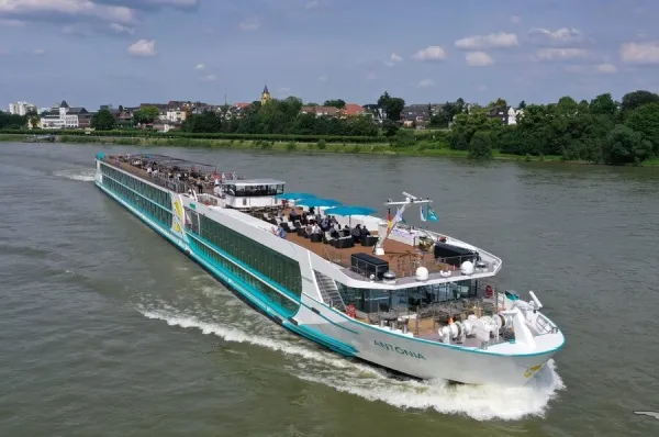 Die MS Antonia auf dem Fluss, im Hintergrund grüne Wälder am Ufer.
