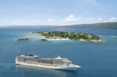 Die MSC Divina auf dem Meer vor einer Insel.