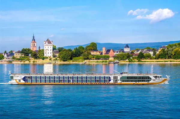 Flusskreuzfahrtschiff der 1A Vista Flotte passiert eine malerische Stadt am Flussufer.