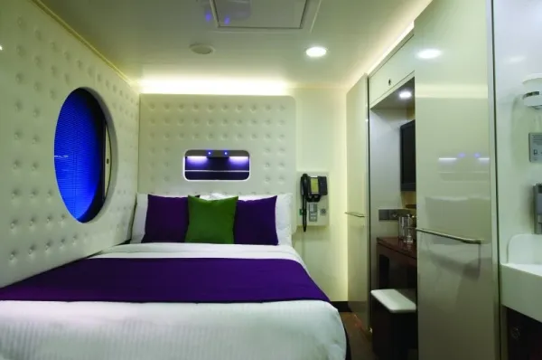 Einzelkabine mit breitem Bett und Bullauge.