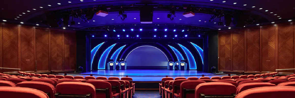 Das große Theater auf dem Schiff Aurora von P&O Cruises, mit Stühlreihen aus rotem Samt und einer großen Bühne im Hintergrund.