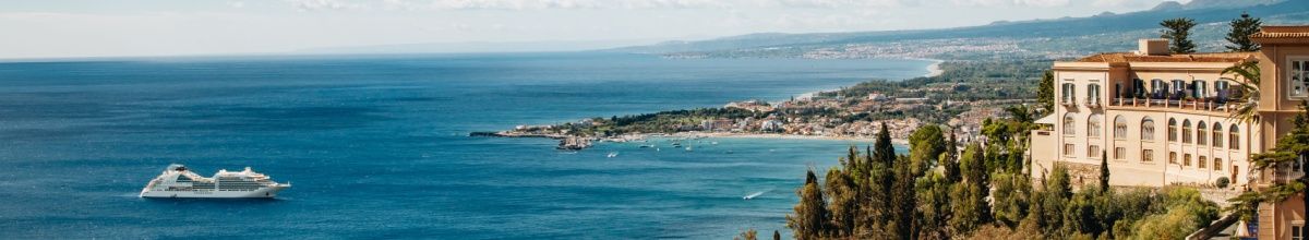 Das Luxuskreuzfahrtschiff Seabourn Ovation von Seabourn an der felsigen Küste von Taormina in Italien.