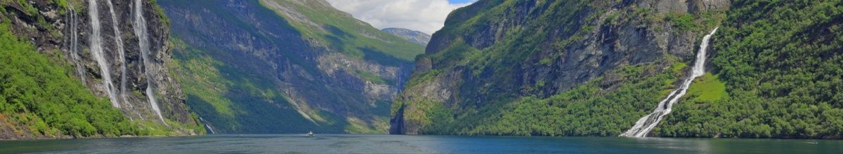 Ein Fjord in Norwegen, eingerahmt von begrünten Bergen und Wasserfällen bei sonnigem Wetter.