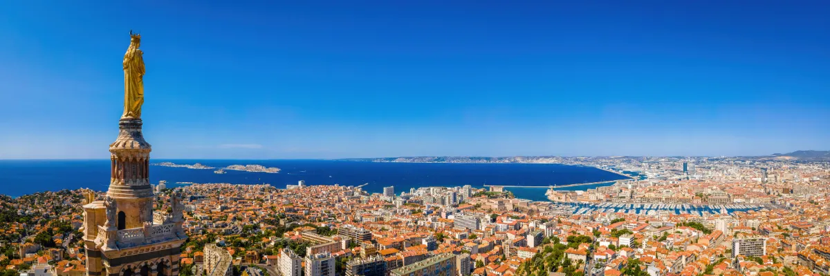 Blick von der Kathedrale Notre Dame de La Garde über Marseille. Rechts die goldene Marienstatue auf dem Glockenturm, im Hintergrund das Mittelmeer.