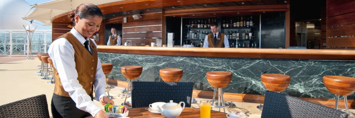 Exzellenter Service, der Ihnen die Wünsche von den Augen abliest - im MSC Yacht Club Special Mehrere Kellner bereiten eine stilvolle Außenbar auf einem MSC Schiff vor.