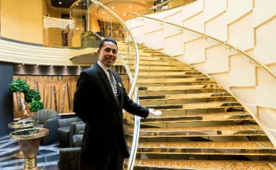 Ein professioneller MSC Yacht Club Butler begrüßt Sie in einem prunkvollem Atrium an Bord.