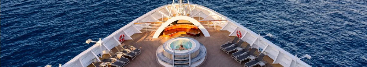 Spitze eines Schiffes von oben fotografiert auf das Sonnendeck, in der Mitte ein Pool und drumherum Sonnenliegen aneinandergereiht.