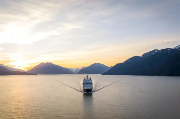 Nieuw Amsterdam Die Nieuw Amsterdam auf dem Wasser vor Sonnenuntergang hinter Berglandschaften.